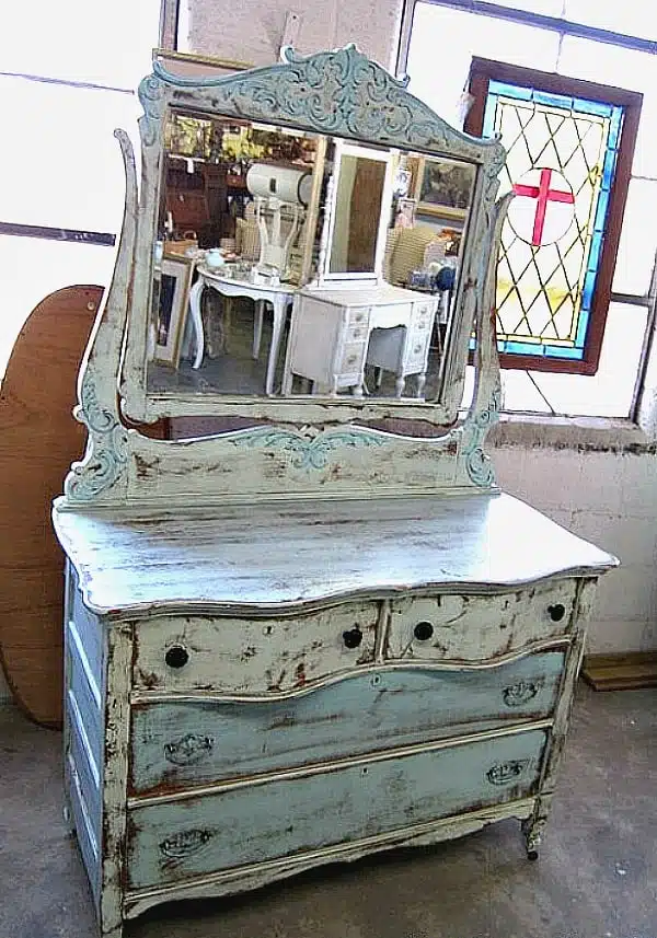 A Two Tone Turquoise Paint Finish Highlights Details On An Antique Wood Dresser