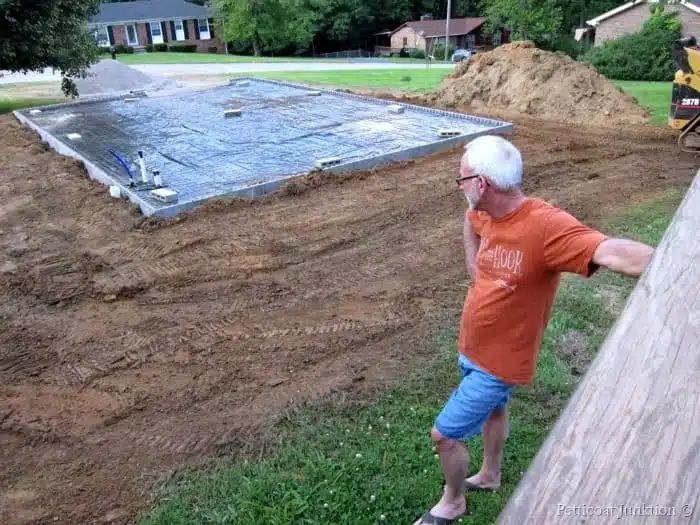 Ray looking at workshop foundation where construction is happening finally