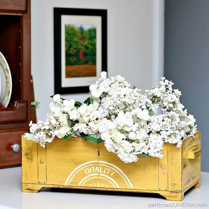 yellow painted box filled with artificial hydrangeas