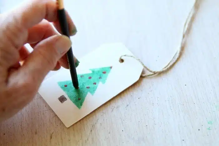 using the tip end of a stencil brush to make ornaments on a tree
