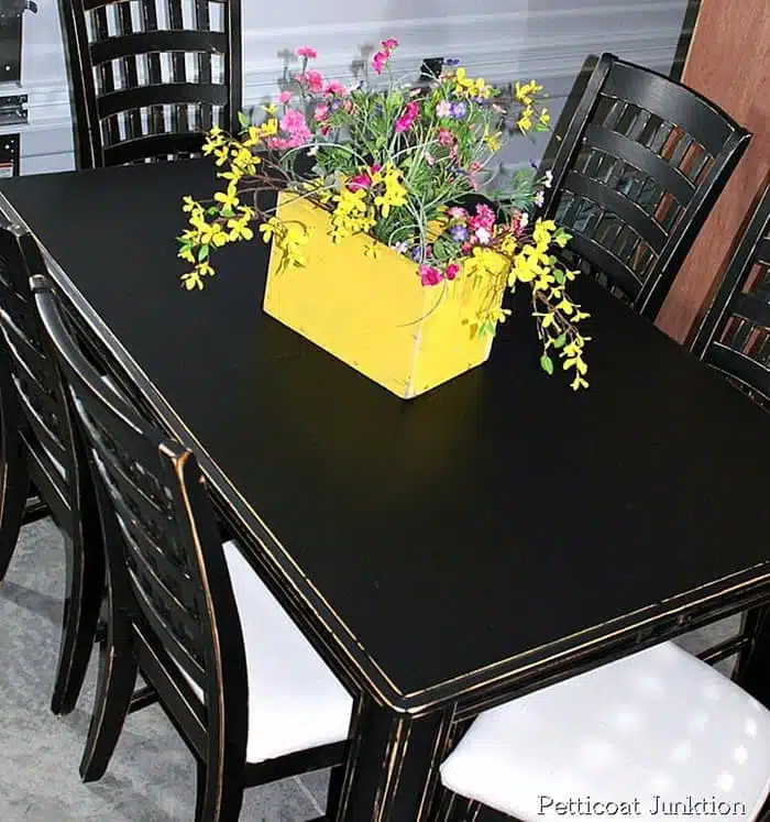 black dining room table and chairs with drop cloth covered seats