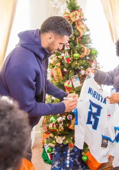 Marcus Mariota Titans Quarterback signing football jersey for Habitat homeowner as part of Homes for the Holidays project