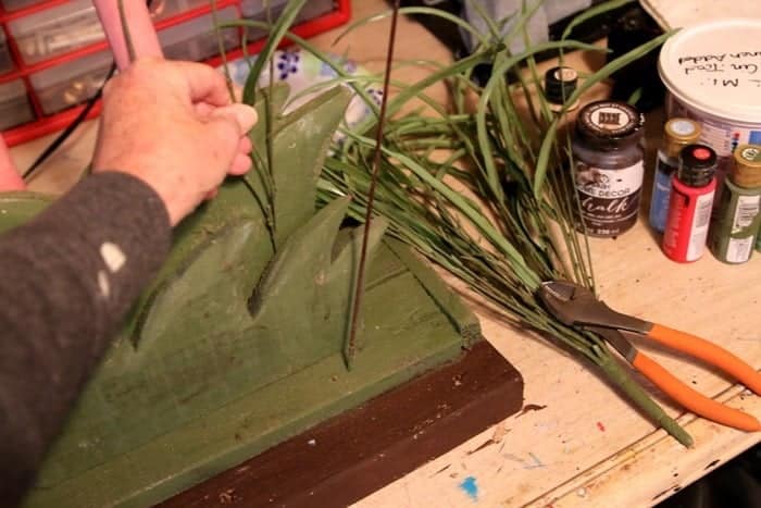 adding artificial greenery to a wood flamingo planter