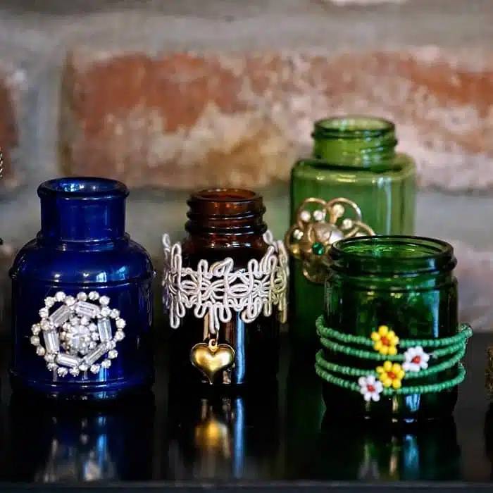 small colored bottles decorated with bits and pieces of jewelry
