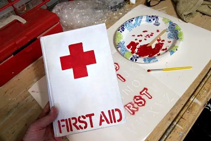 painting an old book to look like a Red Cross First Aid book