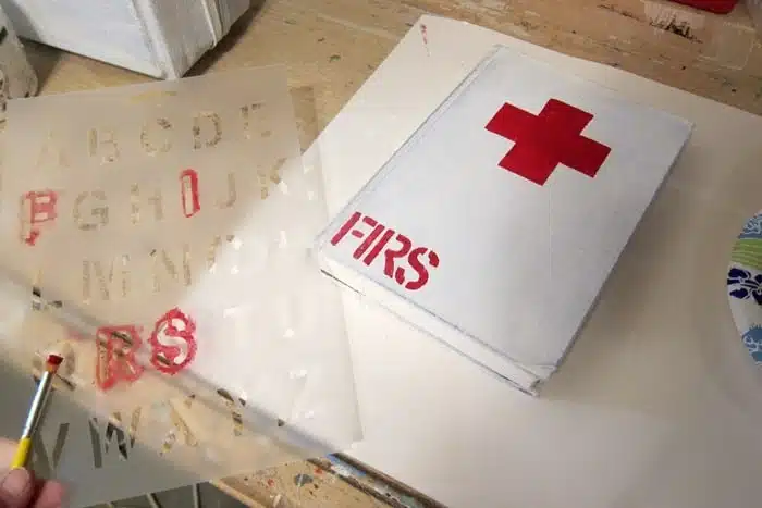 stenciling a painted book to look like an antique red cross first aid book