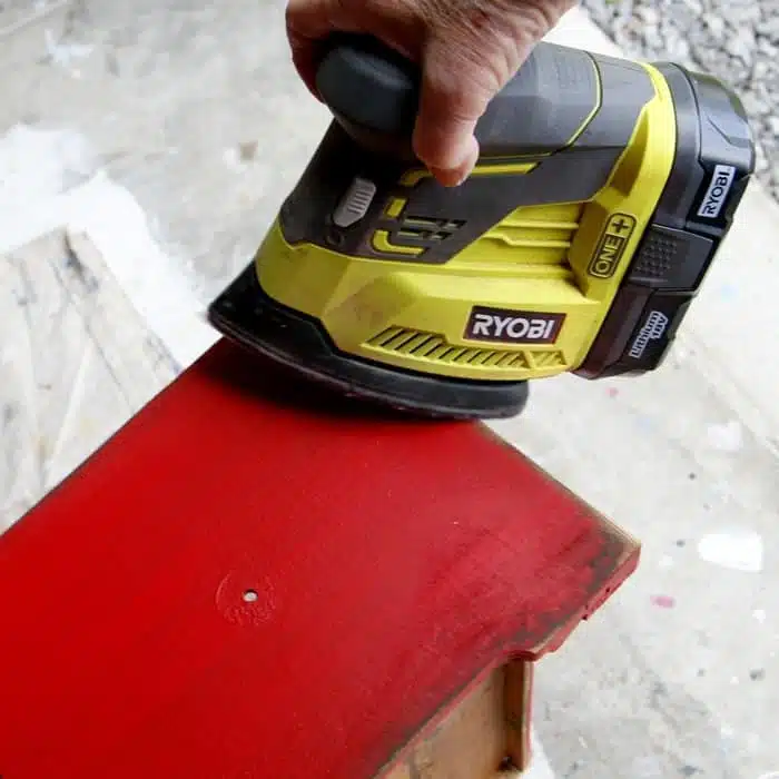 using a battery powered sander to distress painted furniture