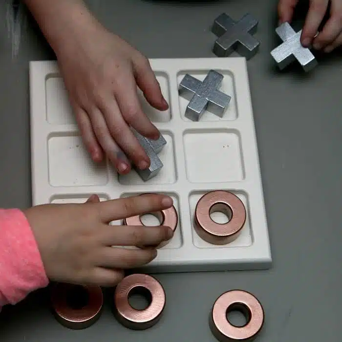 girls playing tic tac toe with metallic painted game pieces