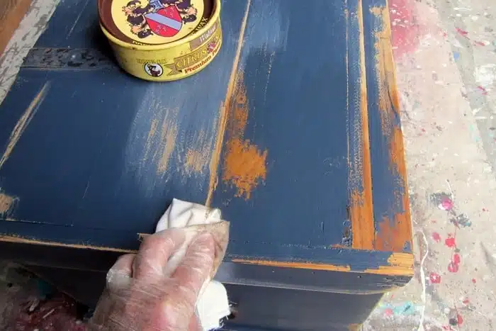 apply a coat of dark wax to distressed paint