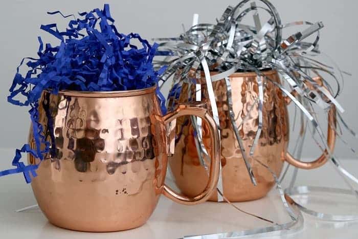 copper mugs filled with shredded paper before adding small gifts to make a gift mug