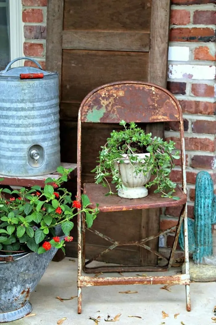 Porch flowers in rusty pots and rusty chairs