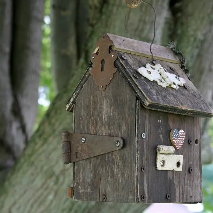 old wood birdhouse decorated with rusty hinges and jewelry