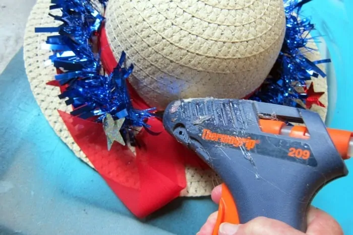 use hot glue to adhere sparkle garland to the hat