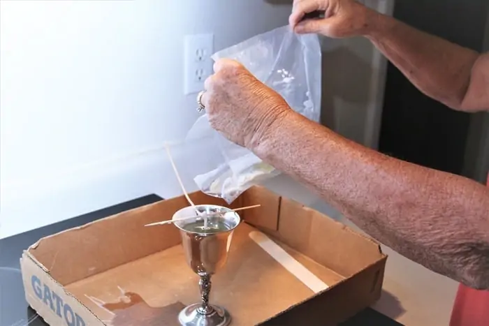 make a candle by pouring melter wax into container with wick
