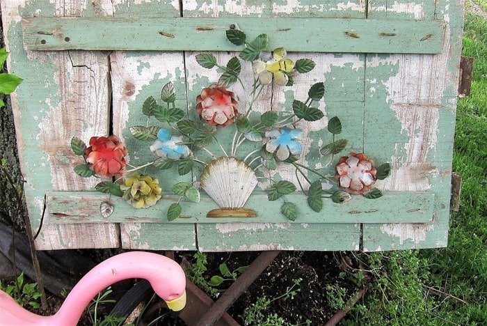 metal flower decor added to a reclaimed wood panel to make garden decor