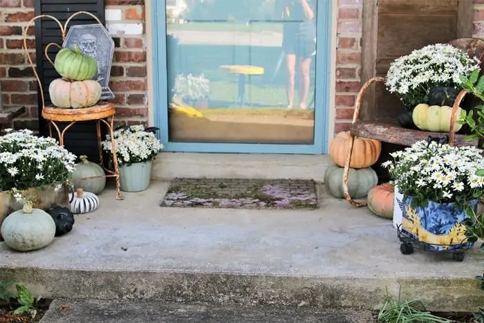 Porch decorations with mums, pumpkins, and rusty chairs