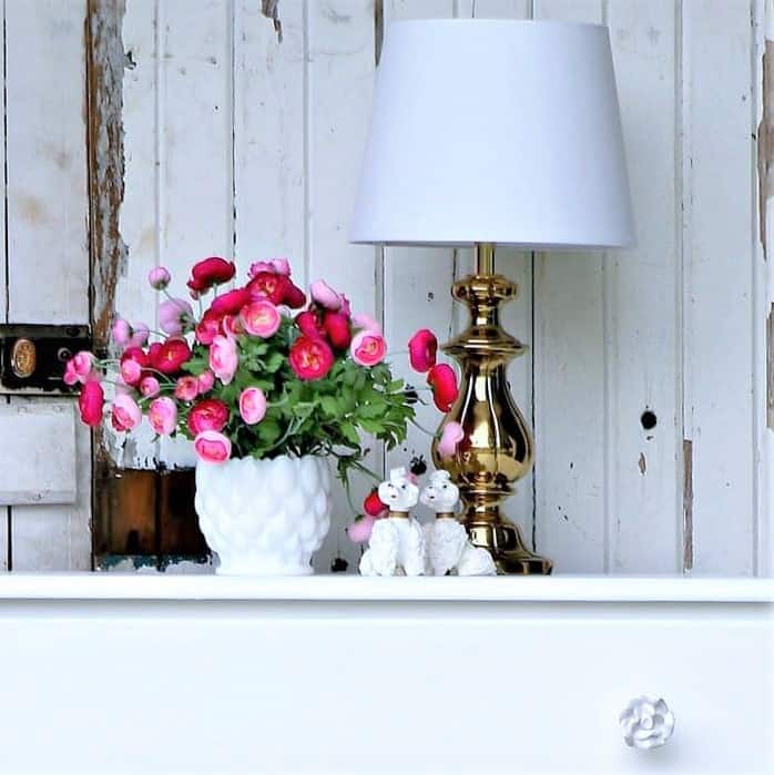 simple white dresser with flower and lamp display