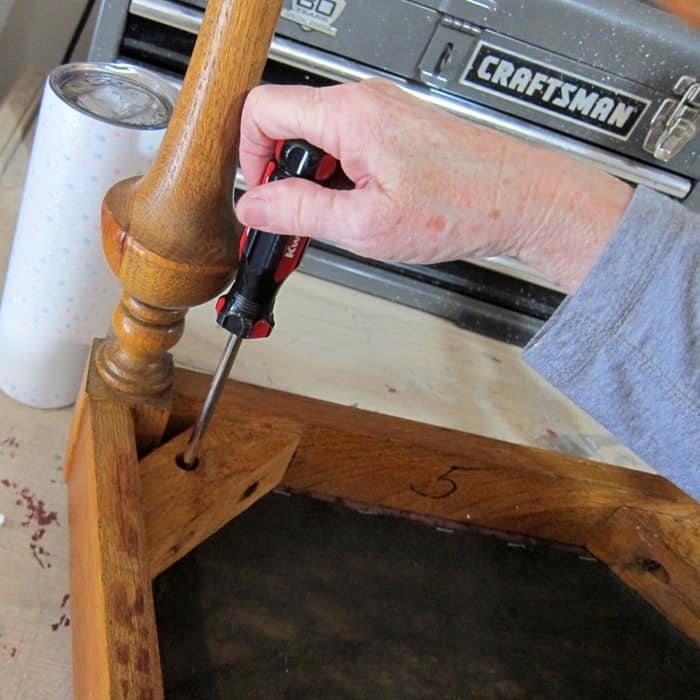 taking the screws out of a dining room chair to remove the seat