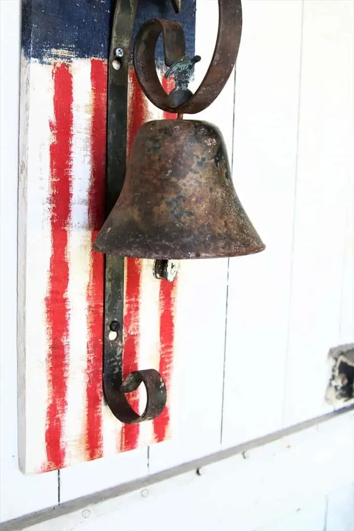 paint a U. S. Flag on rustic wood and add an iron bell