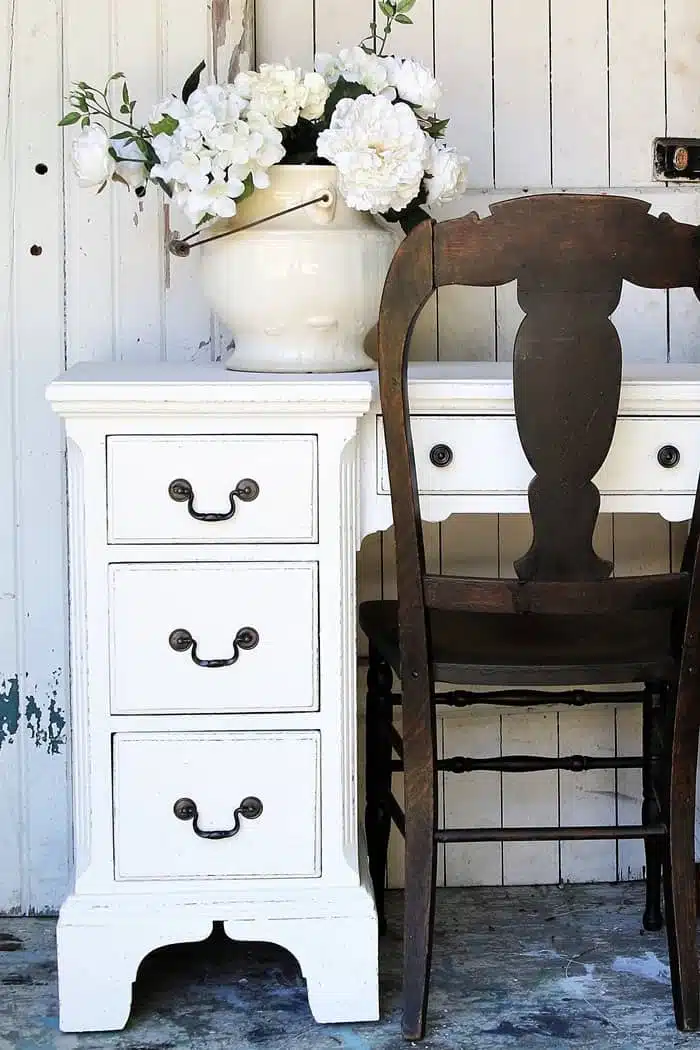 desk painted white with dark metallic hardware and an antique wood chair