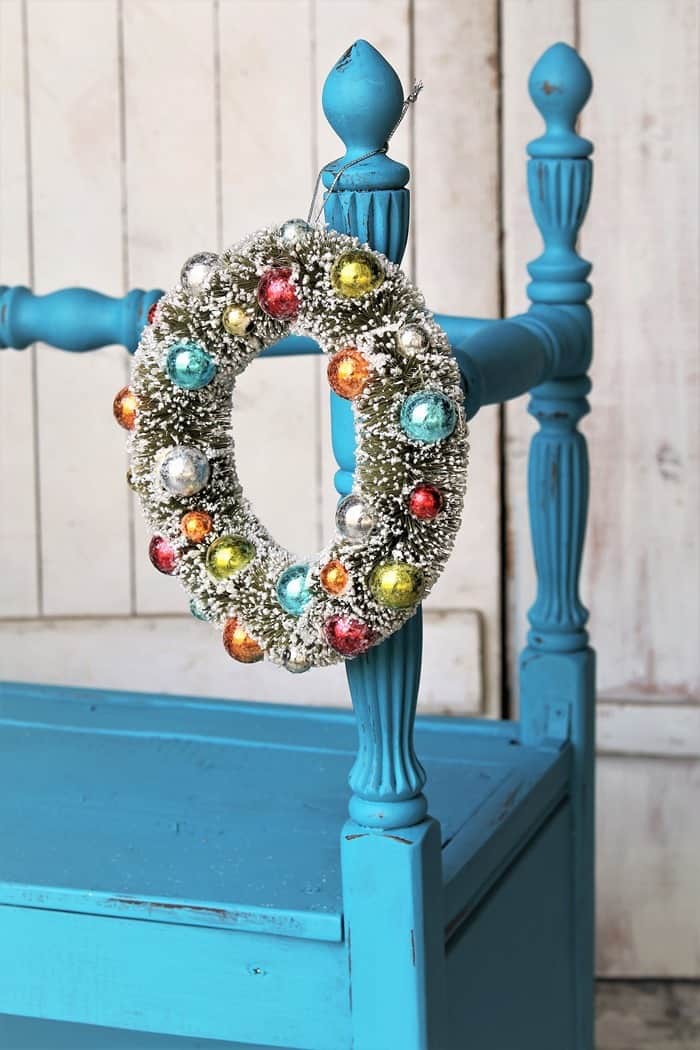 small Christmas wreath hanging from a twin headboard bench painted blue