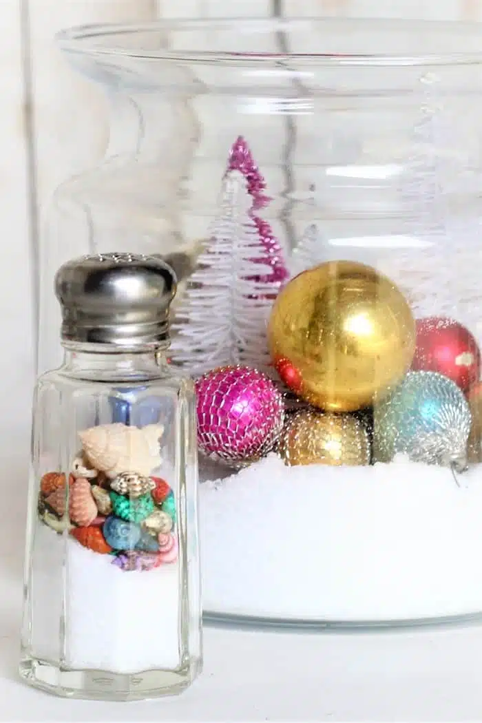 snow scene in a salt shaker and glass ornaments in a large glass container