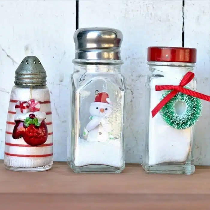 three miniature glass jars and shakers with snow scenes and small wreaths