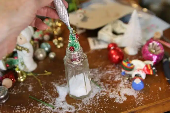 use tweezers to place a miniature items in a small glass jar