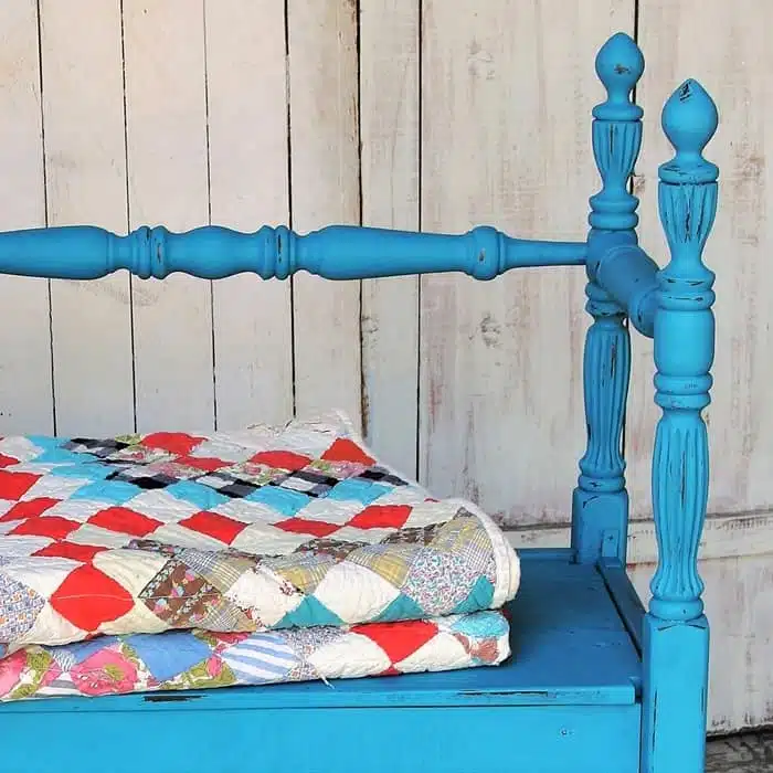 vintage quilt displayed on a painted bench