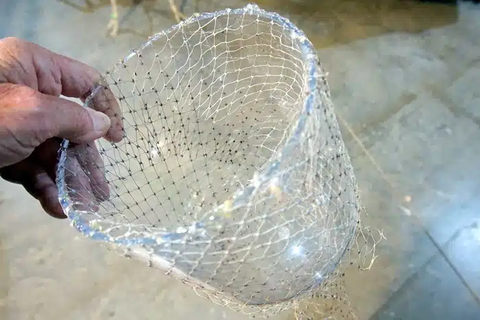how to use hot glue to adhere net bags to a glass cloche to make a beachy coastal display with seashells