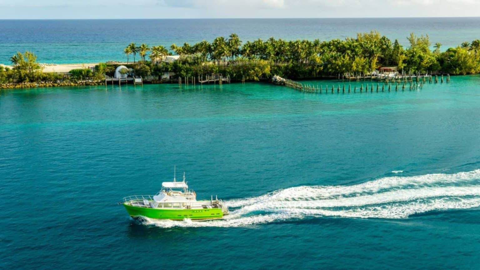 A small recreation boat in the blue Florida waters. Port coastline in the background with a small island protecting a port inlet.