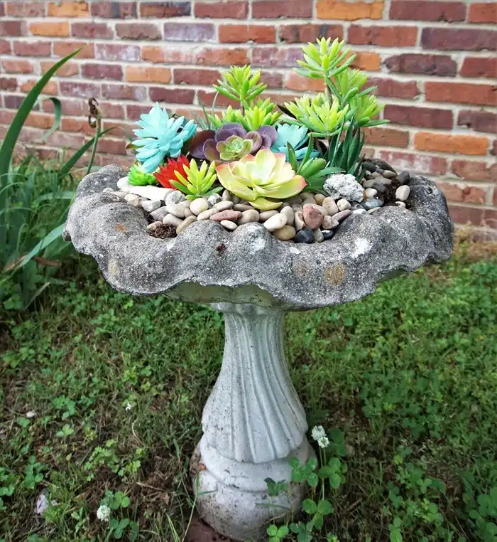 concrete bird bath filled with artificial succulents