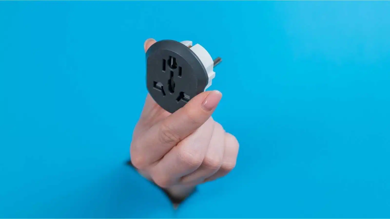 A woman is holding an outlet adapter. A woman's hand sticks out through a hole in a blue background.