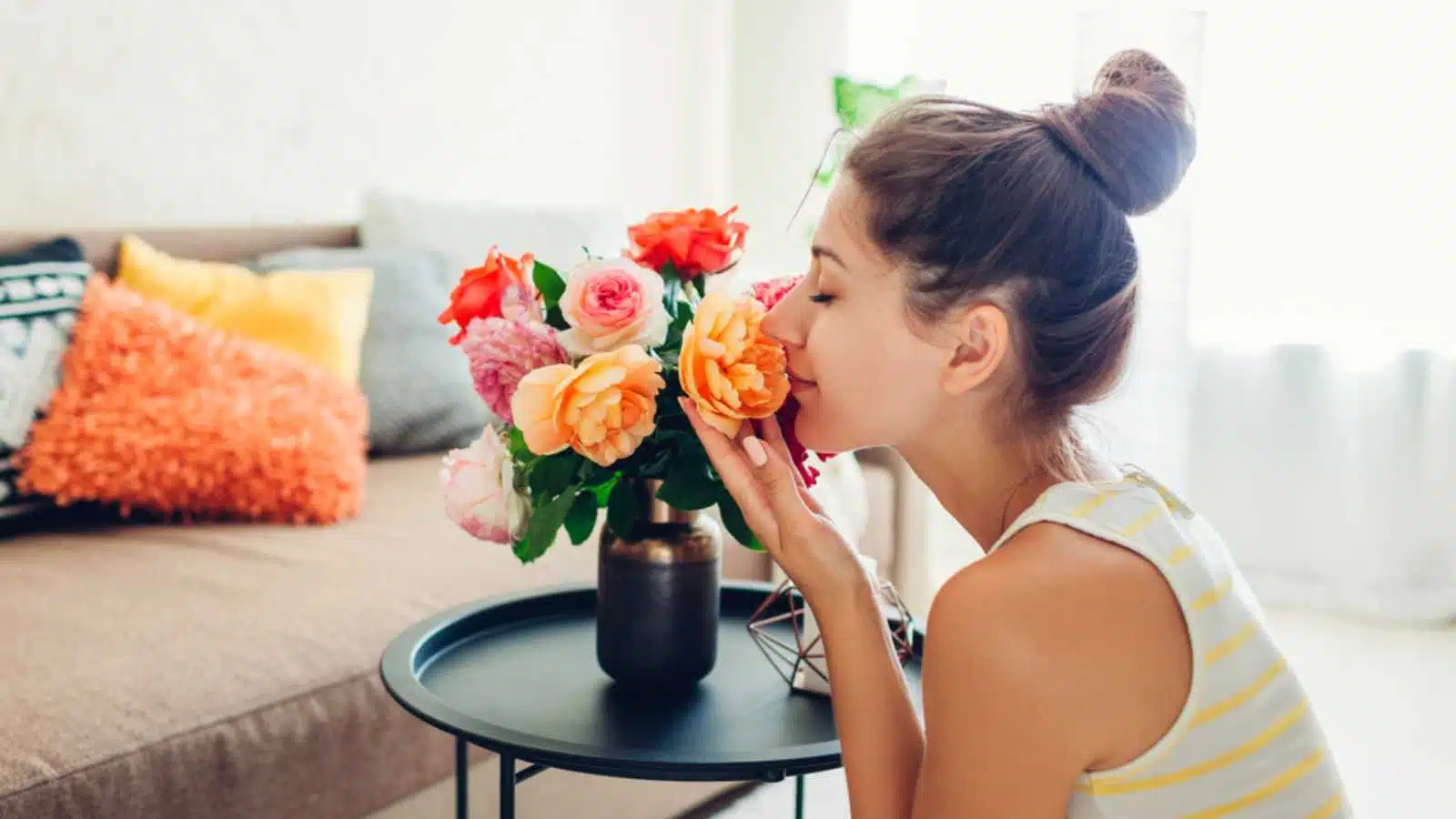 Woman smelling fresh flowers in room