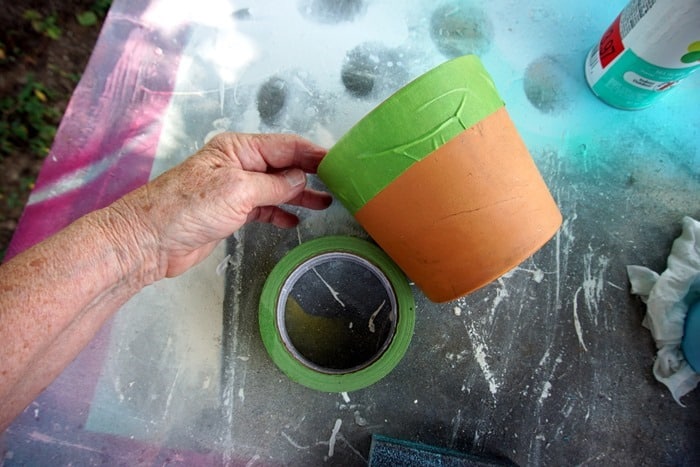 use painters tape on clay flower pots to make a design before painting