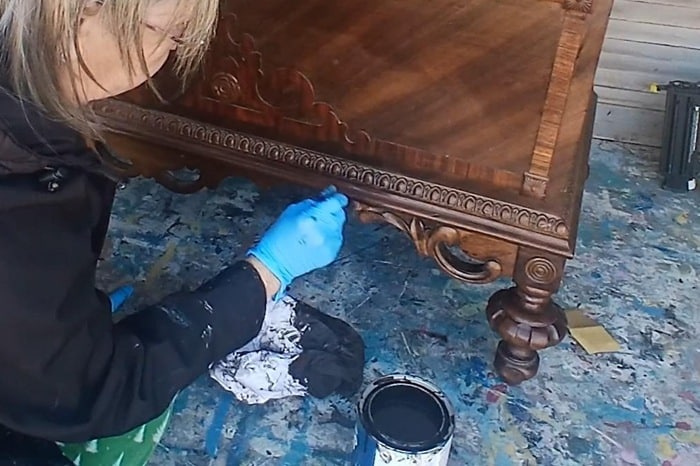 using a small paint brush to stain furniture details